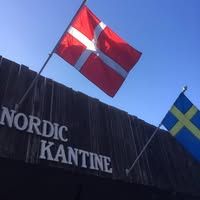 Nordic Kantine exterior sign with Danish and Swedish flags against a clear blue sky